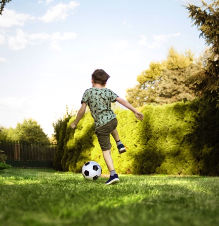 Kid Playing Soccer on Lawn